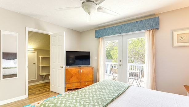 A bedroom with a bed, a TV on a wooden cabinet, a ceiling fan, and a view of the outdoors through a door. - Walk to Ocean & Golf: North Myrtle Beach Home! (North Myrtle Beach)