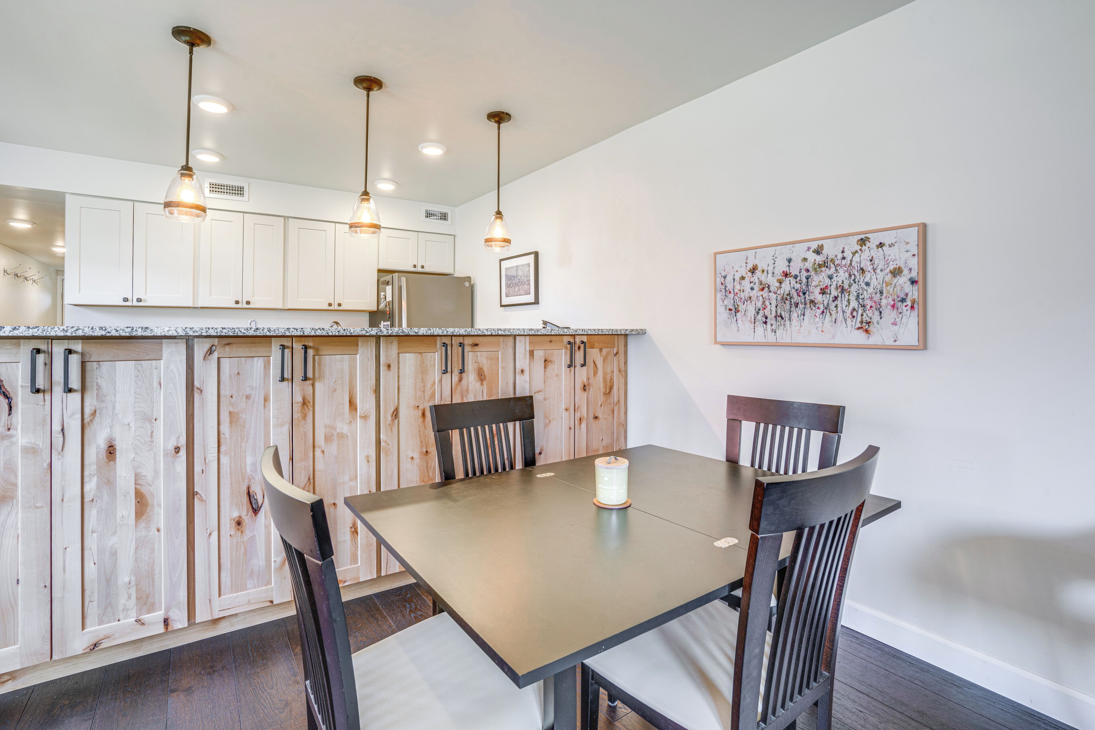 A dining area with a table and chairs, a candle, and wooden cabinets.