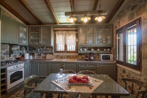 Une cuisine rustique aux murs de pierre, avec des poutres en bois et une table à manger décorée de pommes.
