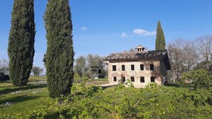 A rustic stone building with a tiled roof, surrounded by lush greenery and tall cypress trees. - New Historic Tuscany Country House Retreat in a Vineyard Near Siena Villa Chiantissimo (Castelnuovo Berardenga)