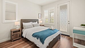 Ein Schlafzimmer mit Bett, Nachttischen, Fenster mit Jalousien und einer Tür mit satiniertem Glas.