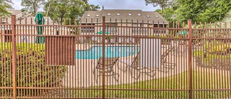A fenced pool area with a house in the background.
