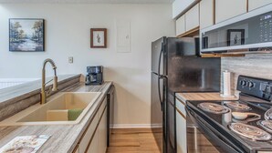 Una cocina moderna con un refrigerador de acero inoxidable, un microondas, una estufa y un lavamanos.