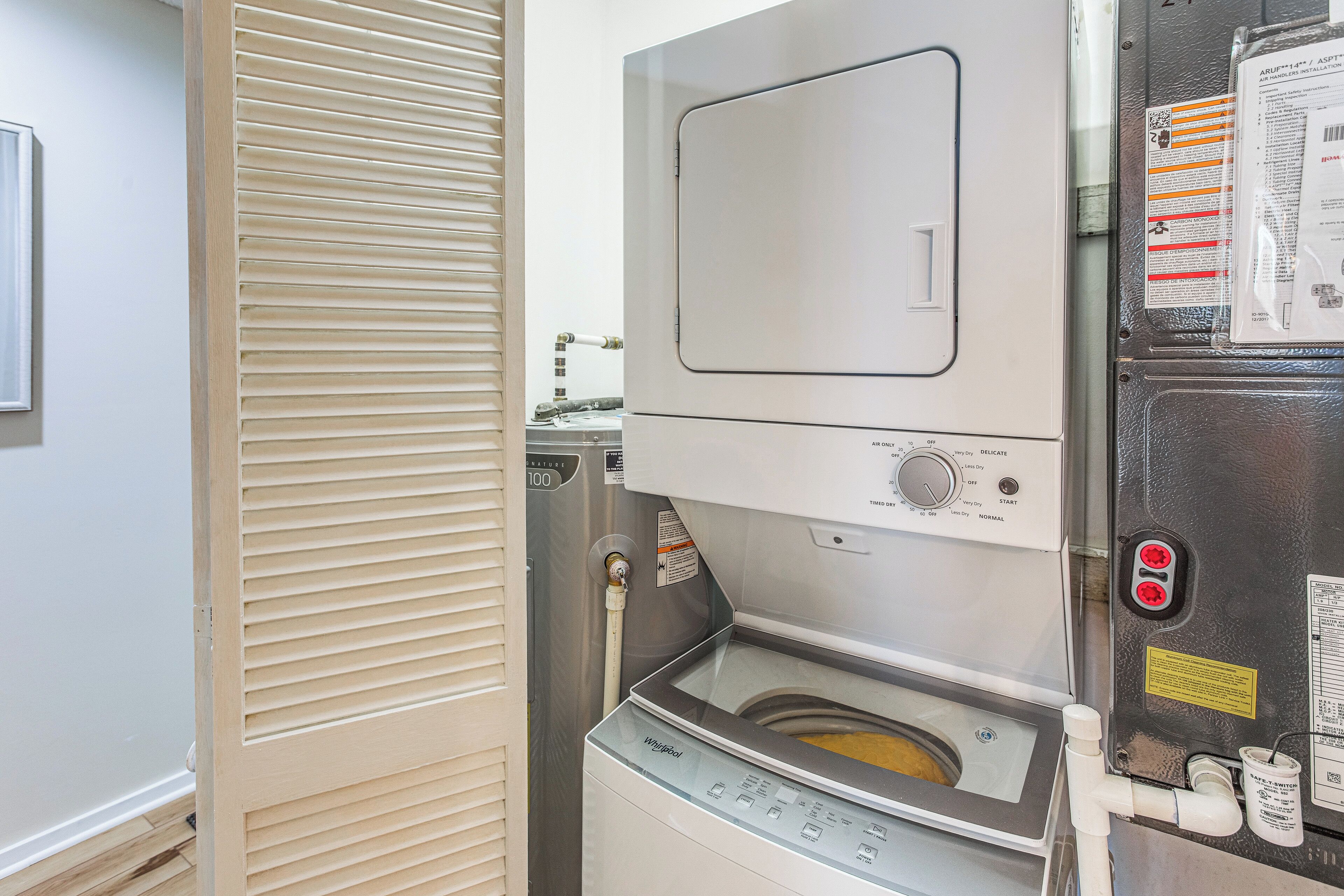 A compact, modern laundry room with a front-loading washing machine and dryer, a control panel, and a water inlet.