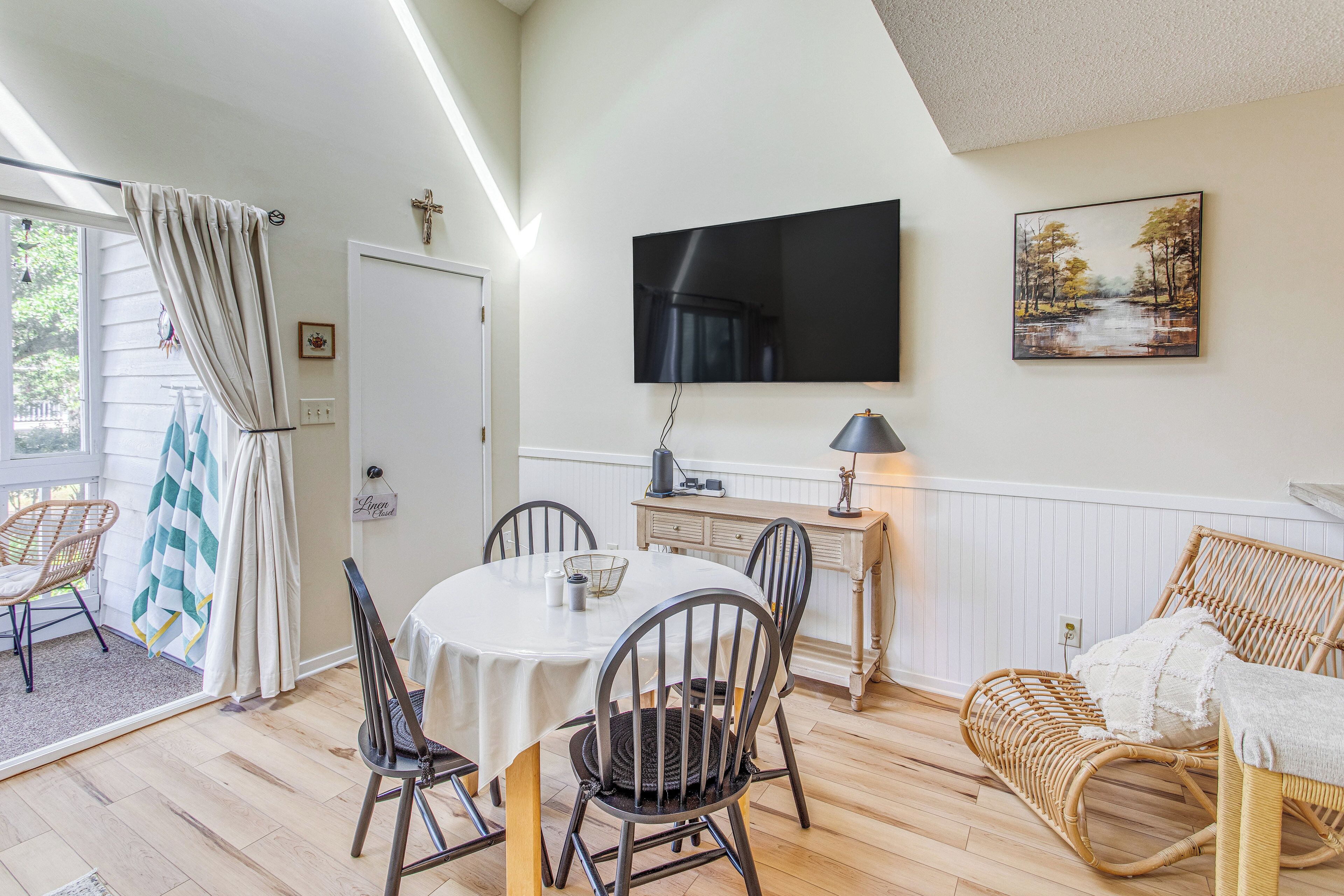 A dining area with a round table, chairs, and a television mounted on the wall.