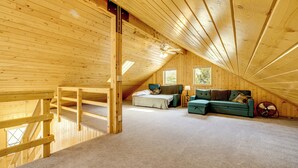 A loft bedroom with a wooden ceiling, a bed, a green sofa, and a fan. - Walk to Sinks Canyon State Park: Spacious Home! (Lander)