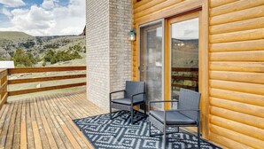 A wooden cabin with a balcony featuring two chairs and a patterned rug. - Walk to Sinks Canyon State Park: Spacious Home! (Lander)