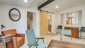 Una sala de estar moderna con un sofá, sillas, una mesa de madera y un espejo grande.