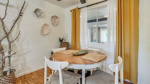 Un comedor con una mesa redonda de madera, sillas blancas y un ventilador de techo.