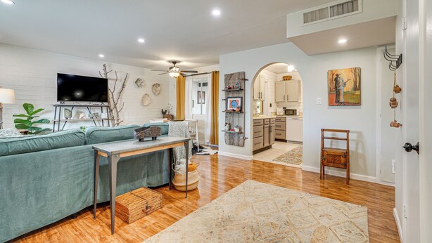 Un salón espacioso con un sofá, una mesa de centro y un televisor. Cuenta con una zona de cocina con armarios y una mesa de comedor.