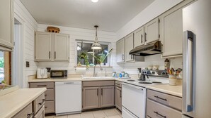 Una cocina moderna con armarios blancos, electrodomésticos de acero inoxidable y una alfombra estampada.