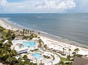 A resort with a large pool, beach, and ocean view.