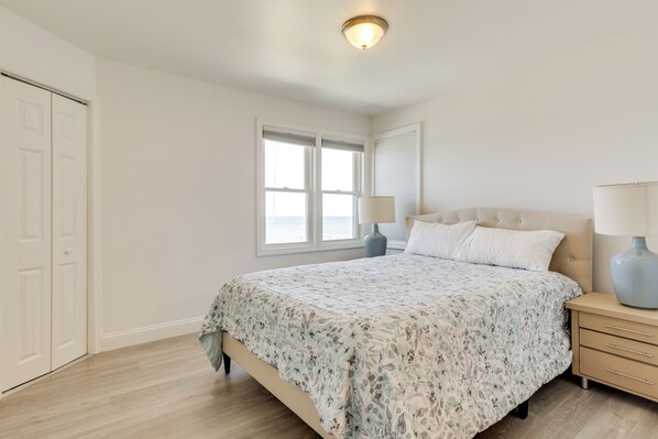 A bedroom with a bed, bedside tables, a window, and a door.