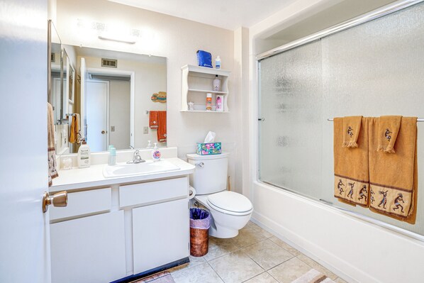 A bathroom with a toilet, sink, mirror, and a glass shower enclosure.