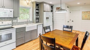 Une cuisine moderne avec des meubles de couleur grise, une table à manger en bois et un four encastré.