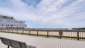 A wooden boardwalk leading to a beach, with a bench and a building in the background. - 1 Mi to Boardwalk: Convenient North Beach Apt! (Owings)