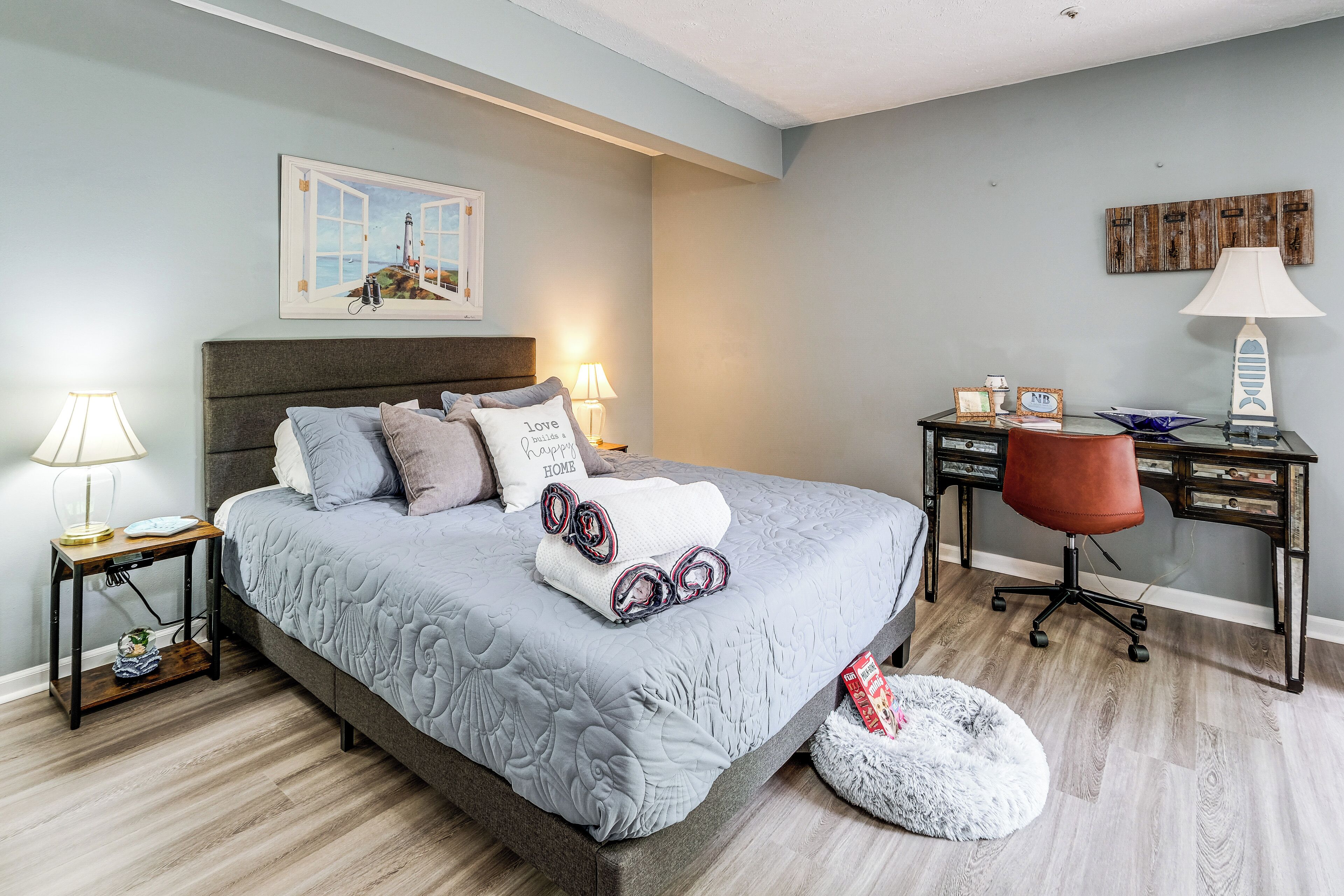 A bedroom with a bed, bedside tables, a desk, and a chair.
