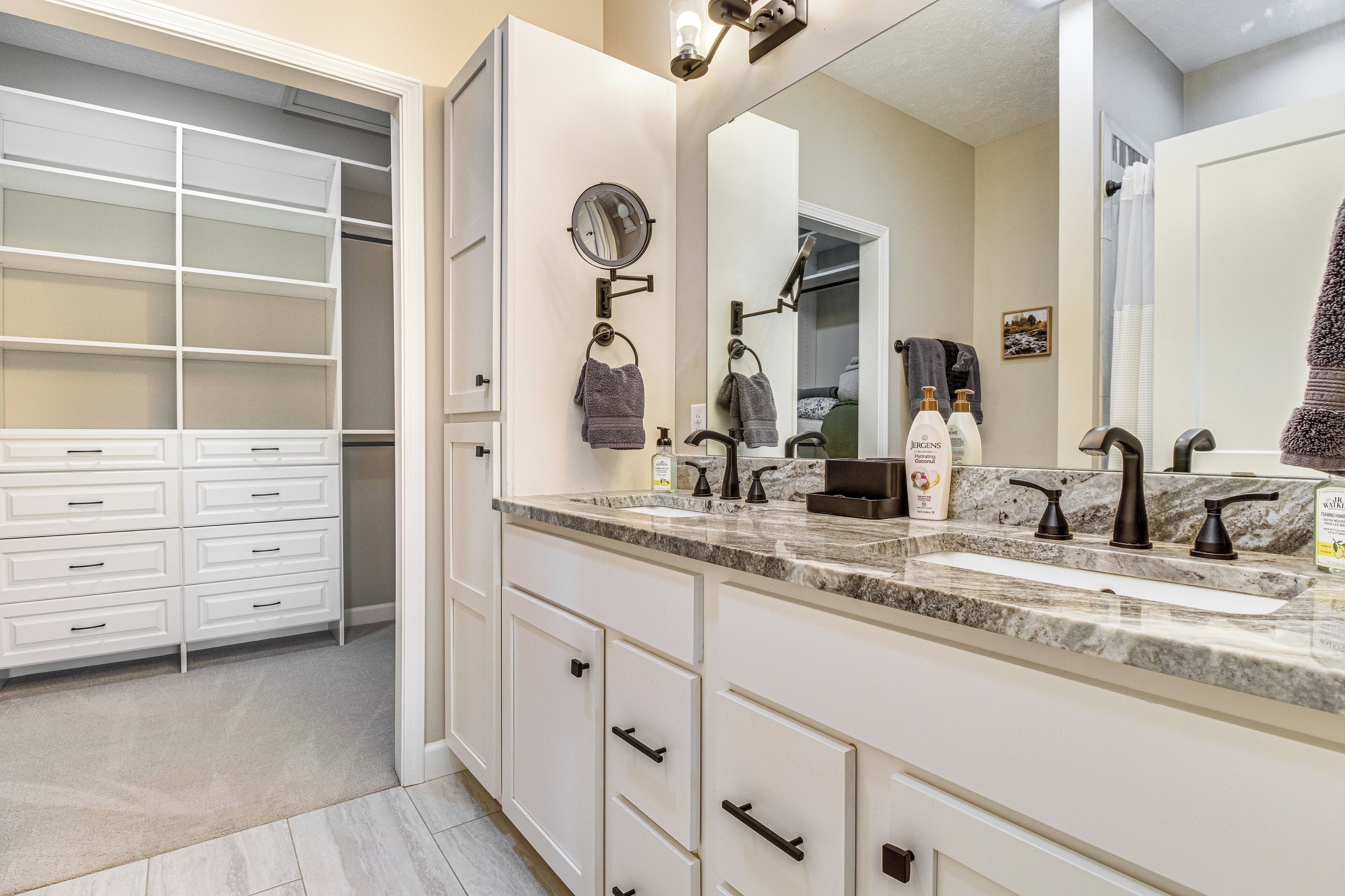 Un baño moderno con lavamanos doble, un espejo grande y un vestidor con varios cajones.
