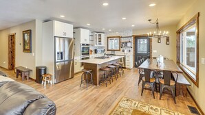 A spacious kitchen with a central island, bar stools, and a dining area with a large wooden table and chairs. - Black Hills Vacation Lodge: New Home! Just Opened! (Newcastle)