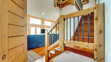 A wooden staircase with a view of a blue sofa and a patterned rug in the background.