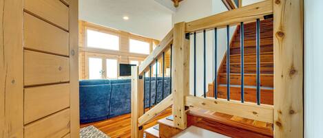 A wooden staircase with a view of a blue sofa and a patterned rug in the background.