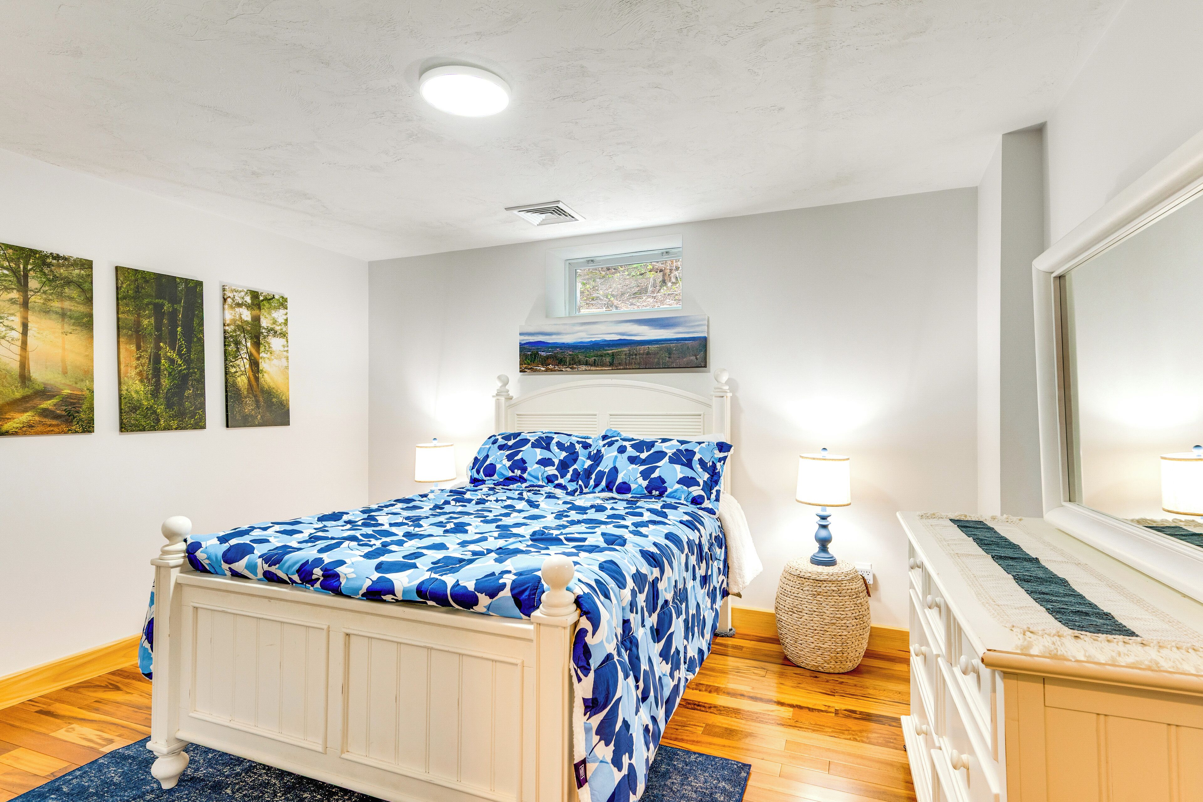 Een slaapkamer met een bed, een raam en kunstwerken aan de muur.
