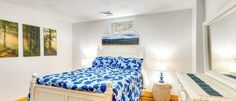 Een slaapkamer met een bed, een raam en kunstwerken aan de muur.