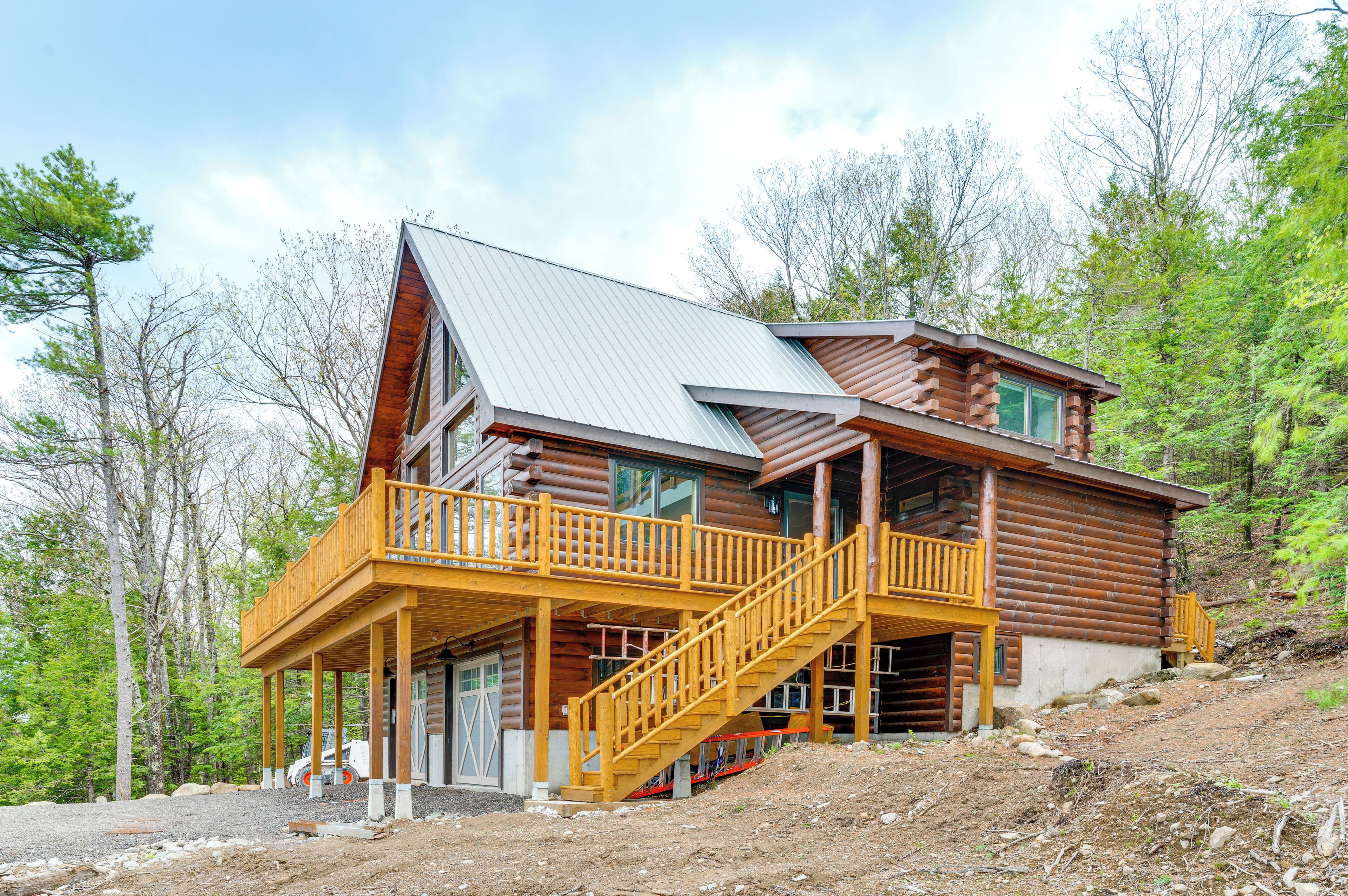 A log cabin with a balcony and a staircase leading to a second floor.