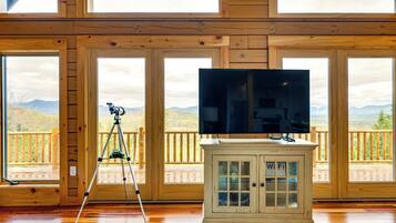 A wooden room with large windows, a tripod, and a cabinet with a Wi-Fi sign.
