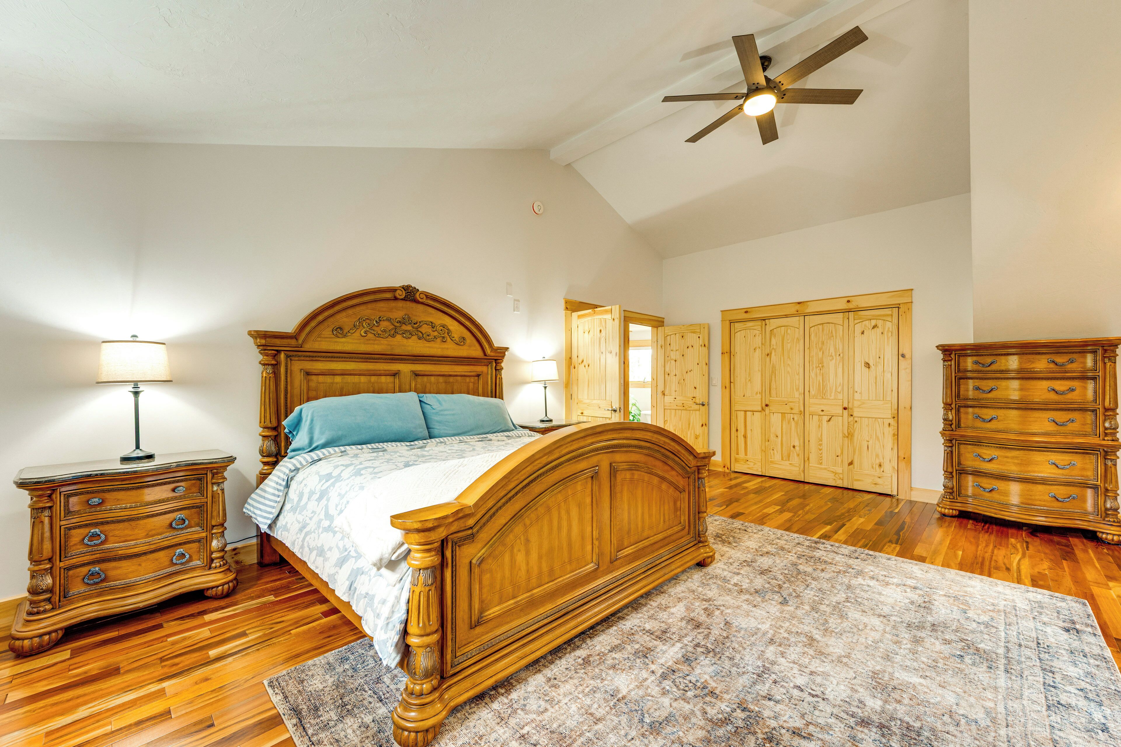 Une chambre à coucher avec un lit en bois, une table de chevet, une commode et un ventilateur de plafond.