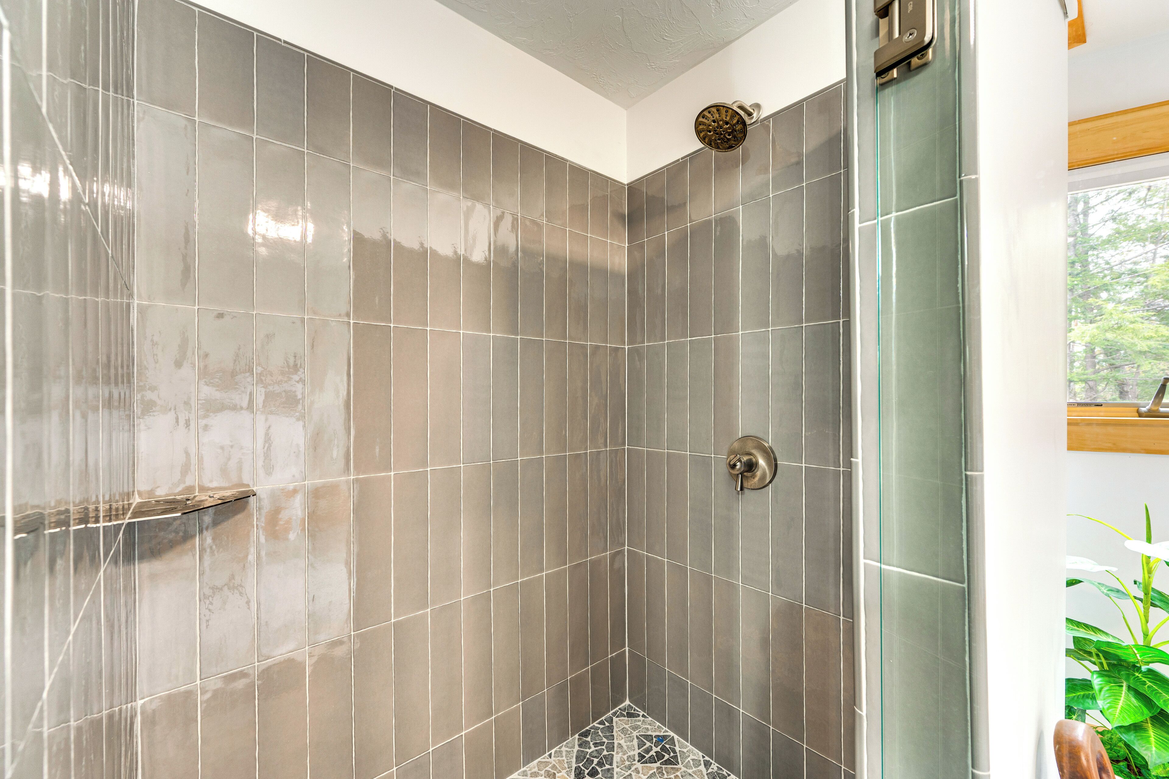 A shower with a glass door, tiled walls, and a corner showerhead.