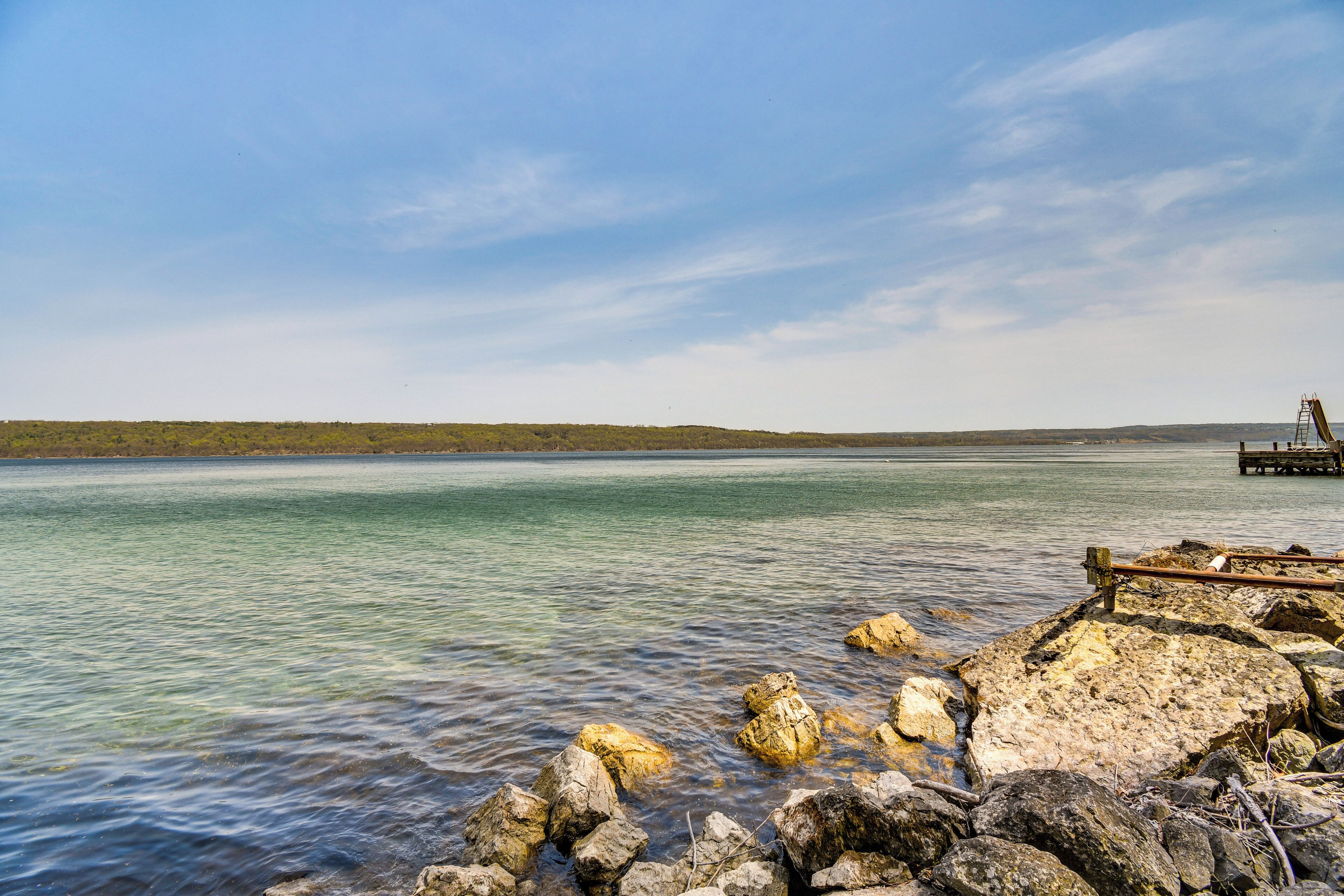 A calm lake with clear water, surrounded by rocky shores and a distant shoreline.