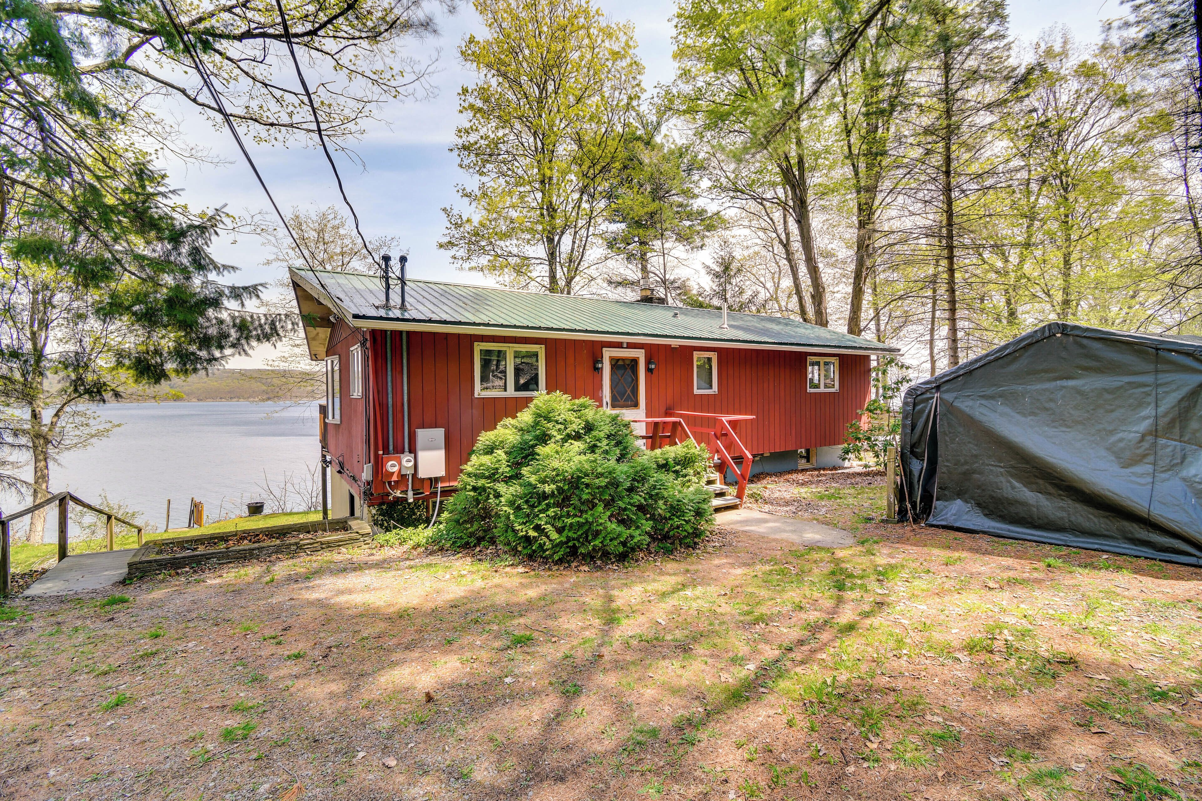 A red cabin with a metal roof, a small porch, and a tent nearby.