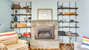 A cozy living room with a stone fireplace, wooden shelves, and patterned furniture. - < 1 Mi to State Park: Trumansburg Cottage w/ Deck! (Trumansburg)
