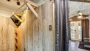 Un interno in legno con una scala, una ventola a soffitto e vista all'esterno attraverso una porta.