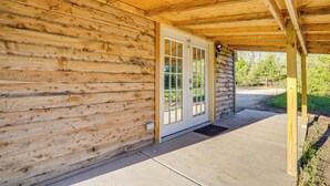 Una baita di legno con un portico coperto, una porta con vetri e un vialetto in cemento che conduce all'ingresso.
