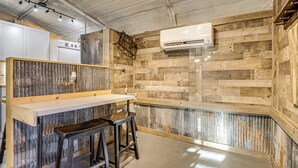 Una cucina con zoccolo in legno, piano di lavoro bianco e due sgabelli.