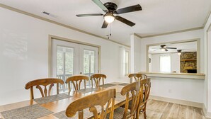 A dining room with a wooden table, six chairs, and a ceiling fan.