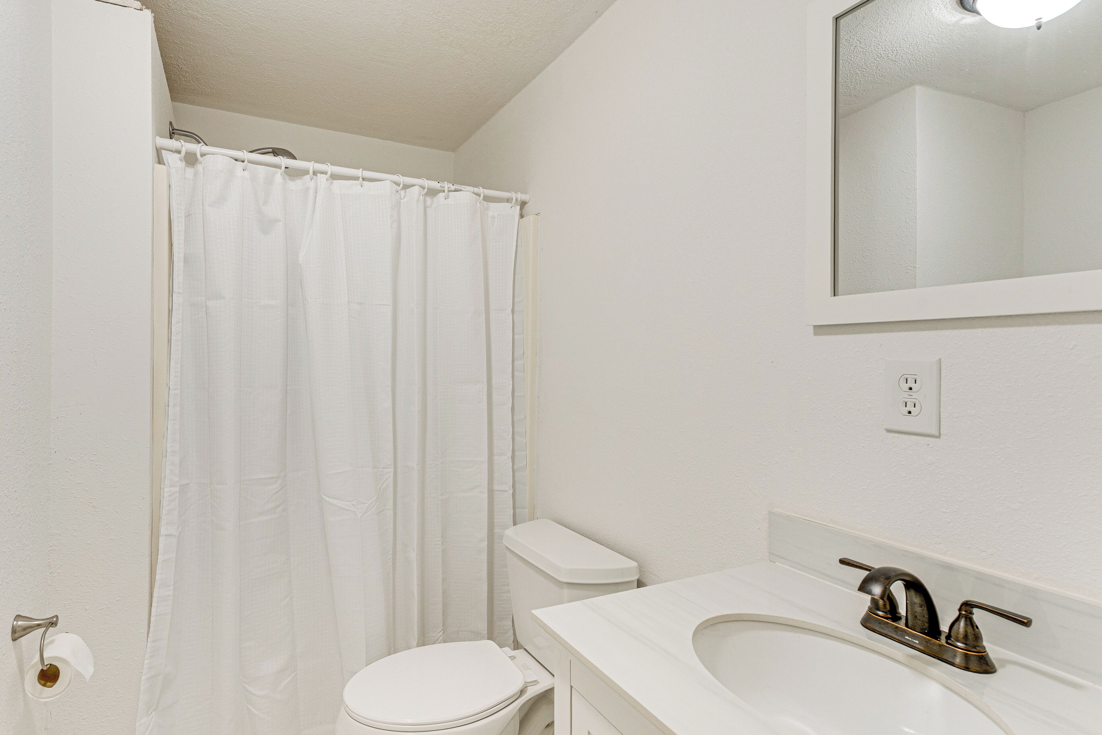 Une salle de bain avec des toilettes, un lavabo et un rideau de douche.