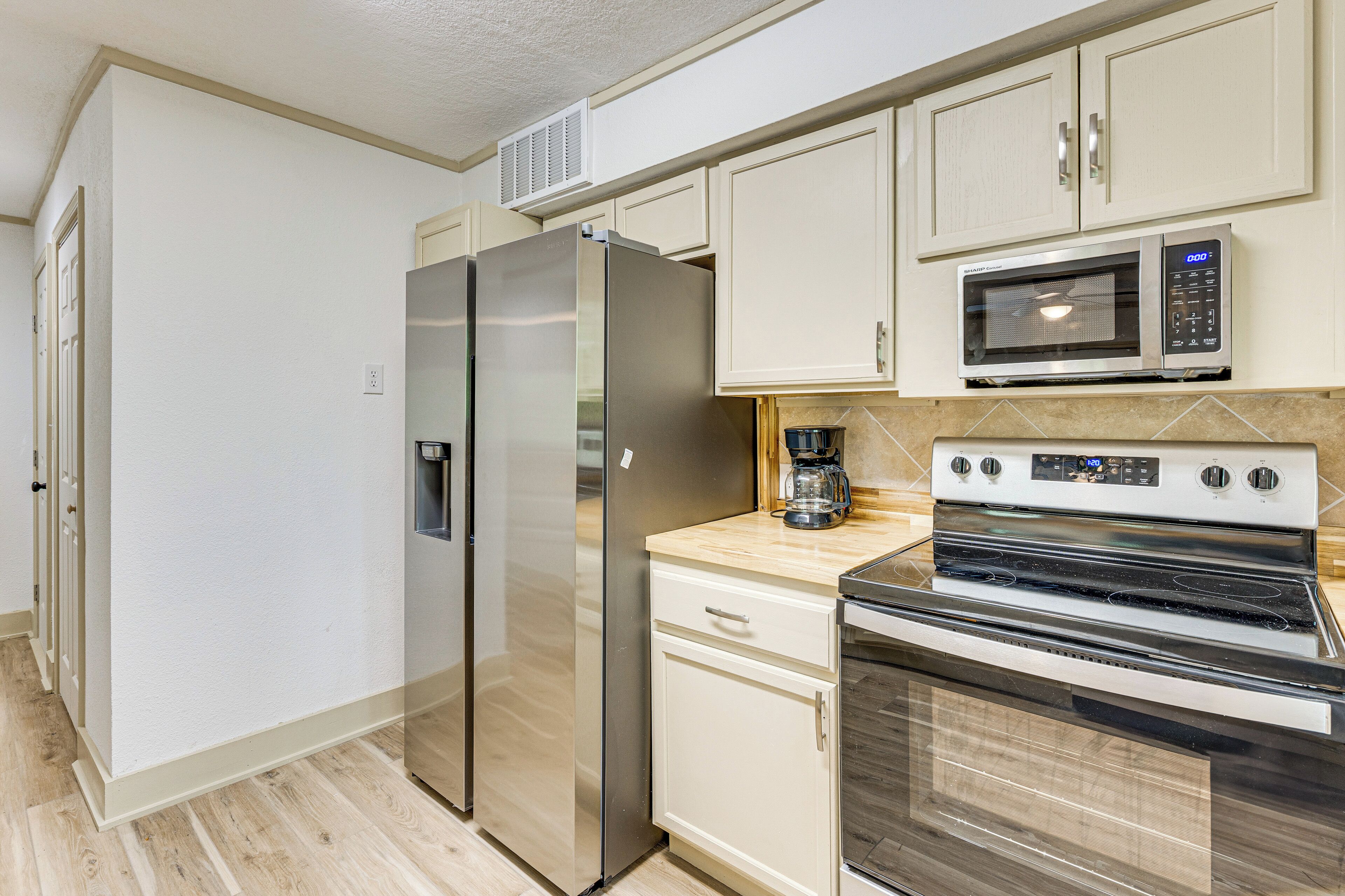 A modern kitchen with a stainless steel refrigerator, a microwave, an oven, and a coffee maker on the countertop.