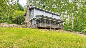 A two-story house with a stone foundation, a balcony, and a stone wall.