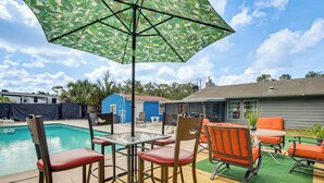 A poolside area with a table and chairs, an umbrella, and a pool. - Homosassa Getaway w/ Pool & Refreshed Lanai (Homosassa)