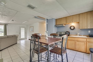 A kitchen with wooden cabinets, a dining table with chairs, a built-in oven, and a clock on the wall. - Homosassa Getaway w/ Pool & Refreshed Lanai (Homosassa)