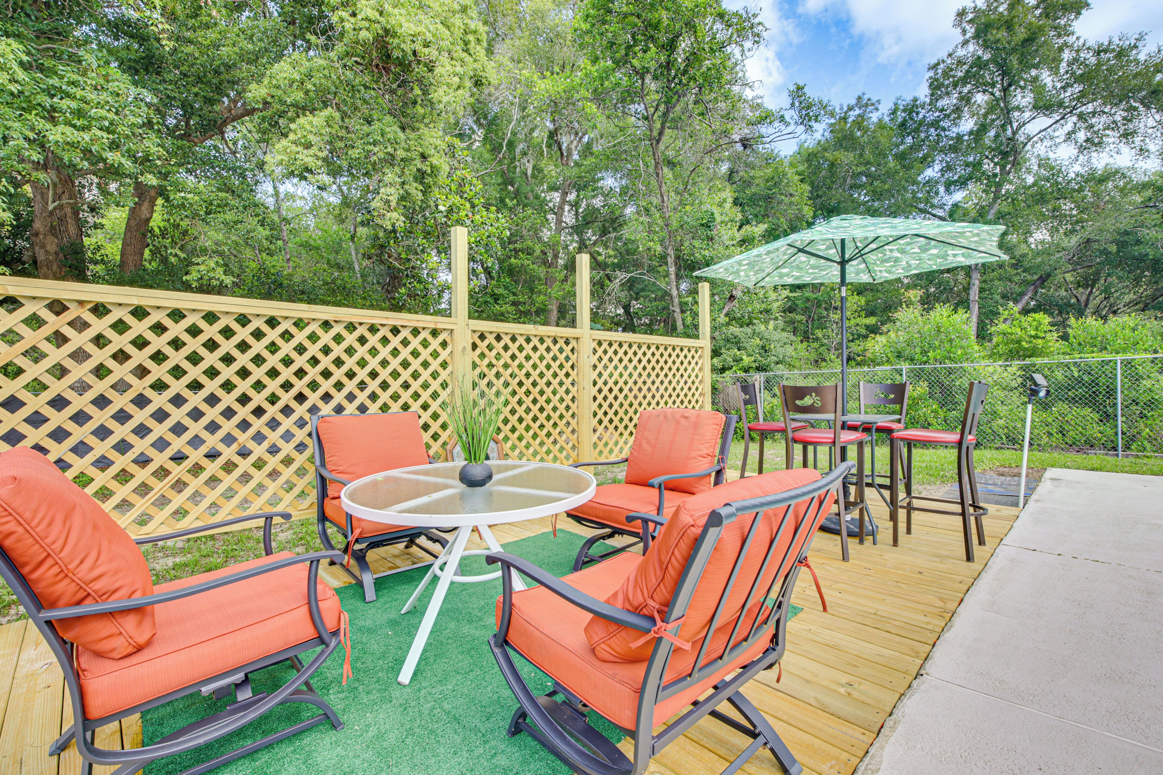 An outdoor patio with a wooden deck, a round table, and orange chairs.