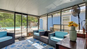 A covered outdoor seating area with wicker furniture, a fan, and a vase with flowers. - Homosassa Getaway w/ Pool & Refreshed Lanai (Homosassa)