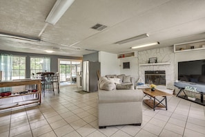 A spacious living area with a sofa, a coffee table, a fireplace, and a kitchen area with a refrigerator and dining table. - Homosassa Getaway w/ Pool & Refreshed Lanai (Homosassa)