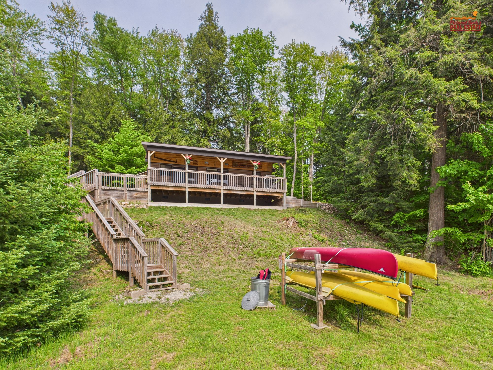 A cabin with a wooden deck and a covered area, surrounded by trees.