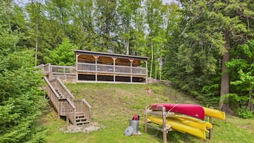 A cabin with a wooden deck and a covered area, surrounded by trees.