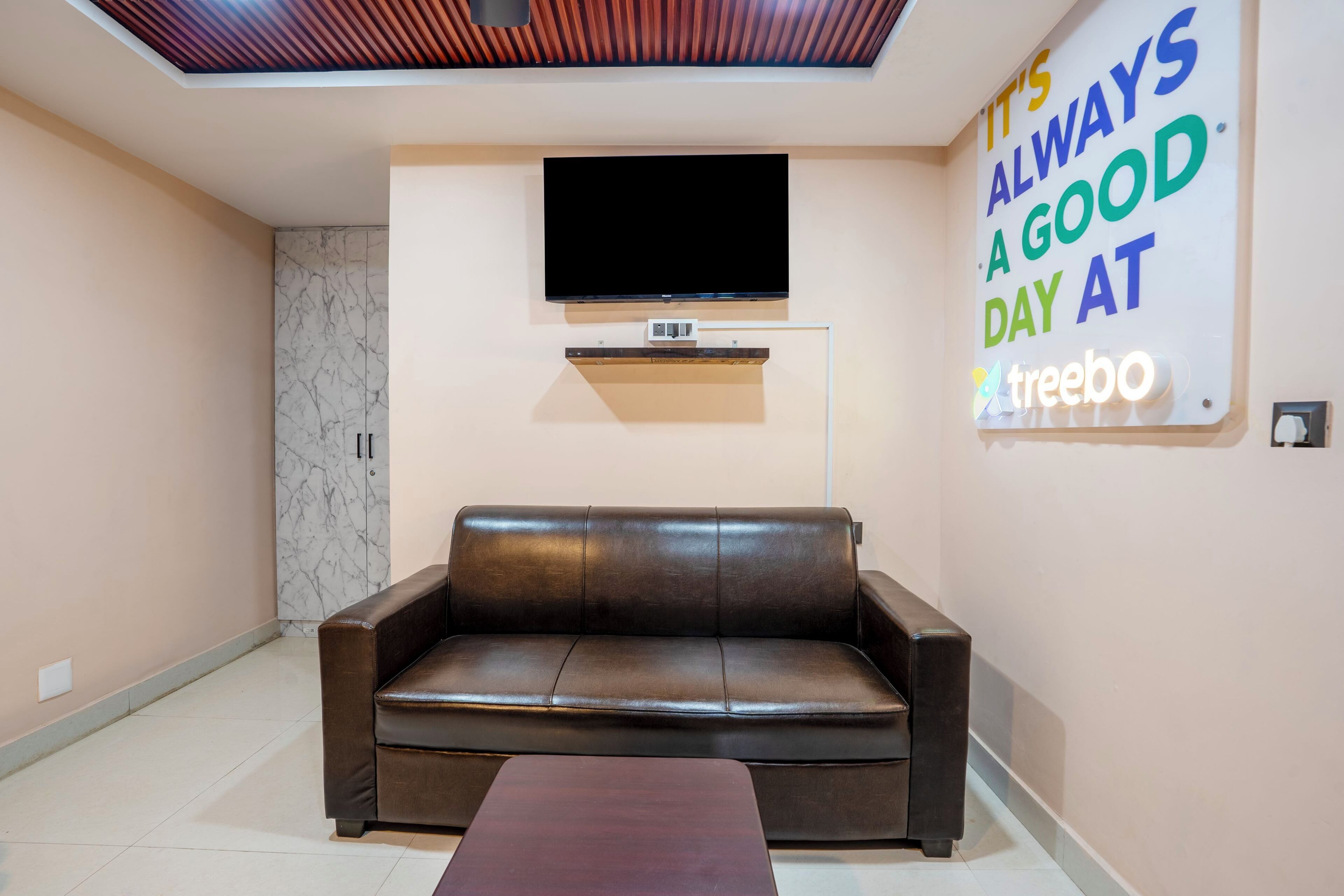 Una sala de estar moderna con un sofá de cuero, un televisor de pantalla plana montado en la pared y un cartel que anuncia un buen día.