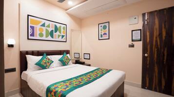 A hotel room with a large bed, a ceiling fan, a wooden wardrobe, and artwork on the walls.